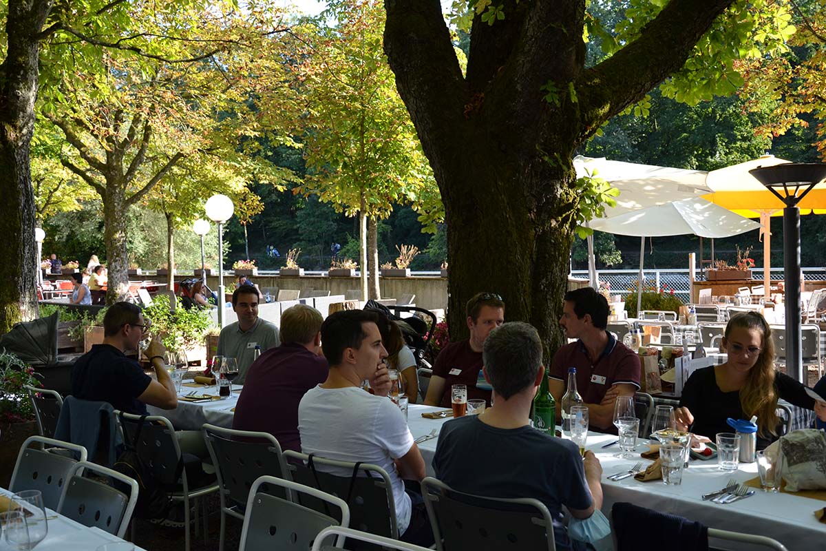 Personen am Tisch essend und sich austauschend